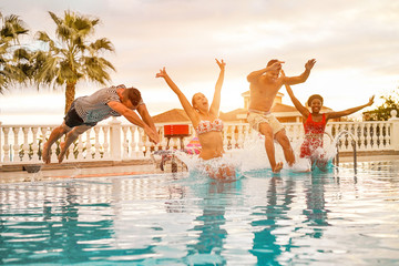 Group of happy friends jumping inside swimming pool