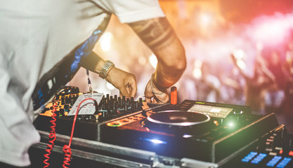 Dj mixing outdoor at beach party festival with crowd of people in background - Summer nightlife...