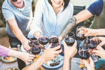 Different age of people cheering with red wine at barbecue dinner outdoor