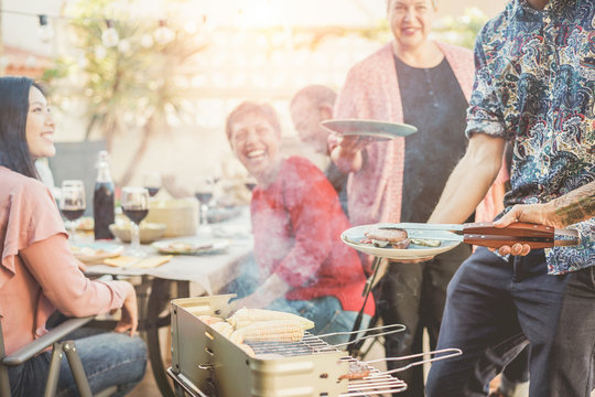 Trendy Man Cooking And Serving Meat At Barbecue Dinner Outdoor - Focus On Hand Tongs