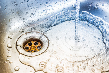 Wasser fließt in einem Edelstahlbecken in den Abfluss