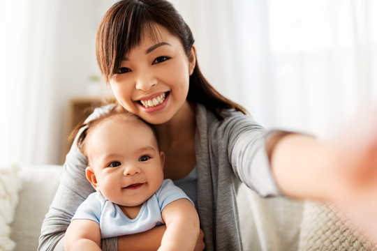 family and motherhood concept - happy young asian mother with little baby son taking selfie