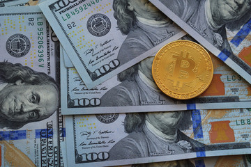 Golden Bitcoin on US dollars. Digital currency. Crypto currency top view. Real coins of bitcoin on banknotes of one hundred dollars. Exchange. Bussiness, commercial.