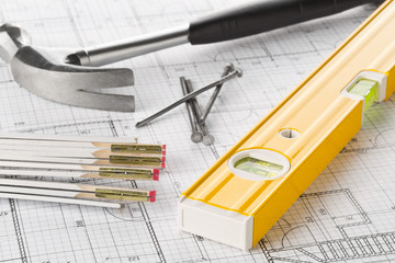 Construction tools  with hammer, nails, folding rule and level on architectural blueprint plan