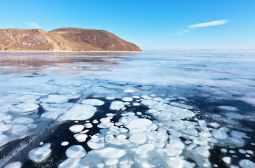 Lake Baikal in February. White bubbles of bottom gases are visible in transparent blue ice. Unusual...