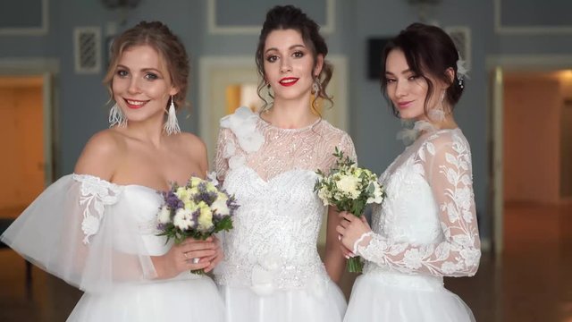 wedding fashion - a portrait of three beautiful brides of European appearance in wedding dresses in a chic room