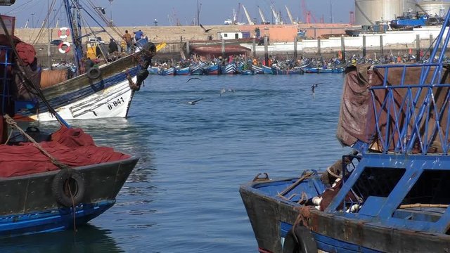 Old tatty fishing trawler passing gap between other ships at Agadir city fishing port in Morocco, Africa