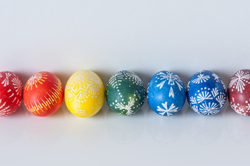 Rainbow line of easter eggs on white background with reflection. Easter holiday concept. Still life with traditional Marguciai, decorated Easter eggs.  Copy space,  close up.