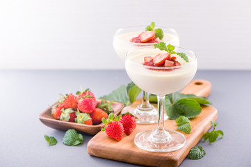 Delicous and nutritious double color (colour) strawberry desserts with mint and diced sarcocarp topping isolated with airy blue background, copy space, close up