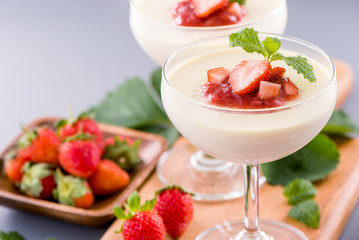 Delicous and nutritious double color (colour) strawberry desserts with mint and diced sarcocarp topping isolated with airy blue background, copy space, close up