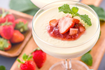 Delicous and nutritious double color (colour) strawberry desserts with mint and diced sarcocarp topping isolated with airy blue background, copy space, close up