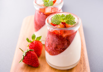 Delicous and nutritious double color (colour) strawberry desserts with mint and diced sarcocarp topping isolated with airy blue background, copy space, close up