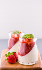 Delicous and nutritious double color (colour) strawberry desserts with mint and diced sarcocarp topping isolated with airy blue background, copy space, close up