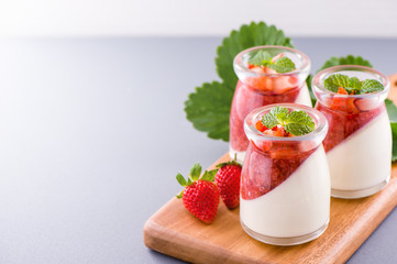 Delicous and nutritious double color (colour) strawberry desserts with mint and diced sarcocarp topping isolated with airy blue background, copy space, close up