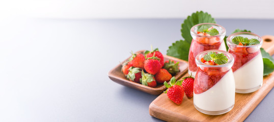 Delicous and nutritious double color (colour) strawberry desserts with mint and diced sarcocarp topping isolated with airy blue background, copy space, close up