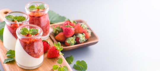 Delicous and nutritious double color (colour) strawberry desserts with mint and diced sarcocarp topping isolated with airy blue background, copy space, close up