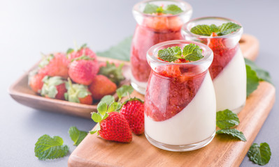 Delicous and nutritious double color (colour) strawberry desserts with mint and diced sarcocarp topping isolated with airy blue background, copy space, close up