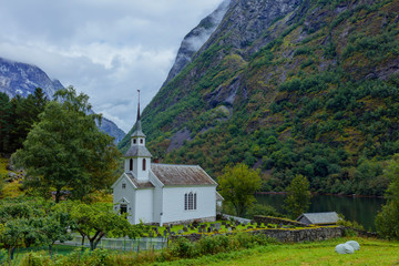 Fototapeta na wymiar Church with a cemetery stands on the shore of the fjord, Norway