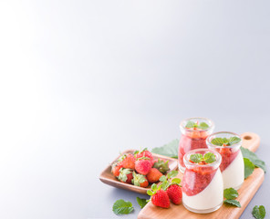 Delicous and nutritious double color (colour) strawberry desserts with mint and diced sarcocarp topping isolated with airy blue background, copy space, close up