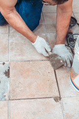 Laying tiles at home. Construction worker laid floor tiles, selective focus