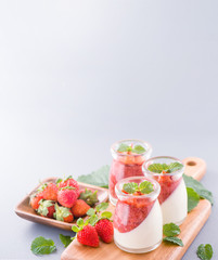 Delicous and nutritious double color (colour) strawberry desserts with mint and diced sarcocarp topping isolated with airy blue background, copy space, close up