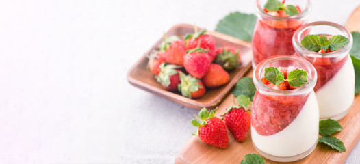 Delicous and nutritious double color (colour) strawberry desserts with mint and diced sarcocarp topping isolated with airy blue background, copy space, close up