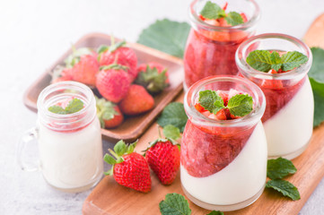 Delicous and nutritious double color (colour) strawberry desserts with mint and diced sarcocarp topping isolated with airy blue background, copy space, close up