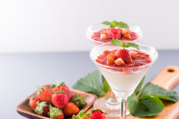 Delicous and nutritious double color (colour) strawberry desserts with mint and diced sarcocarp topping isolated with airy blue background, copy space, close up