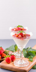 Delicous and nutritious double color (colour) strawberry desserts with mint and diced sarcocarp topping isolated with airy blue background, copy space, close up