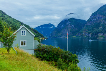 Fototapeta na wymiar Typical countryside Norwegian landscape with green wall house. Cloudy summer morning in Norway, Europe.