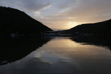 Boats, ships on the Lim Canal, Lim Fjord, Lim Bay. Summer, warm, holiday, evening. Calm, pleasant end of the day. Dusk, twilight, sunset in Croatia. Colorful sky reflecting in the water surface.