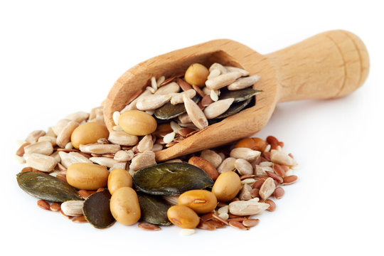 Mix of various healthy seeds including soy beans, sesame, pumpkin and sunflower seeds in wooden scoop isolated on white background