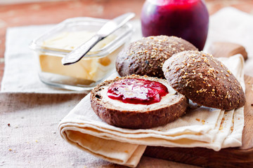 Homemade rye buns with linseeds, sesame and white poppy seeds served with butter and Jostaberry jam