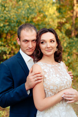 Fototapeta premium young bride and groom walking in autumn Park with yellow leaves