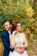 Fototapeta premium young bride and groom walking in autumn Park with yellow leaves