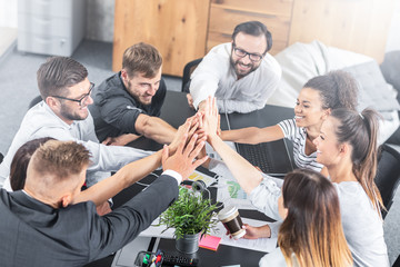 Happy business people team giving high five in office.
