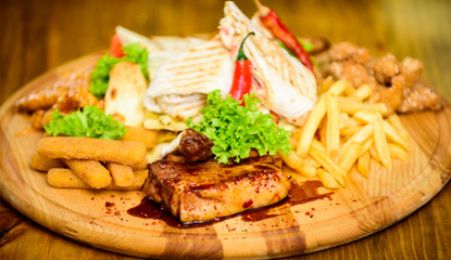 Snack for beer. Wooden board french fries fish sticks burrito and meat steak served with salad. Pub menu snack. Enjoy your meal. Meat snack for group friends. Tasty delicious snacks. Restaurant food