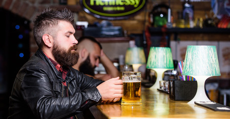 Hipster relaxing at pub. Guy bearded man sit at bar counter in pub. Man with beard spend leisure in dark pub. Brutal hipster relaxing. Weekend lifestyle. Pub great place to dine drink and have fun
