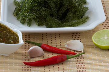 Sea grapes or green caviar and spicy sauce on a white dish the wooden dish made of Japanese style bamboo