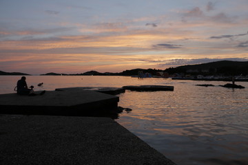 People watching the sunset on the seashore. Summer, warm, holiday, evening. Twilight on the Adriatic Sea in Croatia. Vodice. Colorful, orange, blue sky. Beautiful dusk. Pleasant, calm end of the day.