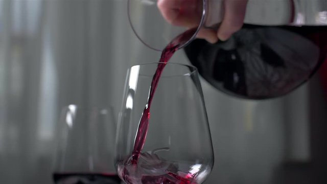 Pouring red wine from the count into a cup of slow motion
