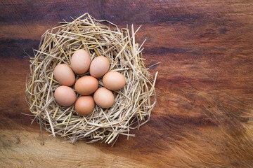 Top view of Chicken, Easter eggs in nest on a wooden table background, image with copy space.
