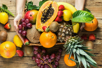 Young caucasian woman holds in hands box with raw organic tropical and seasonal summer fruits...