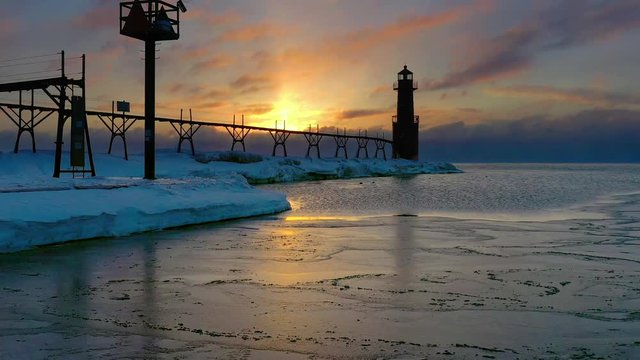 Aerial view of frozen, icy harbor and lighthouse with fog at dawn.