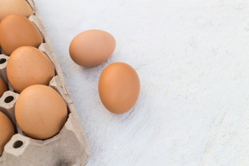Brown eggs in package on a white wooden table, image with copy space.
