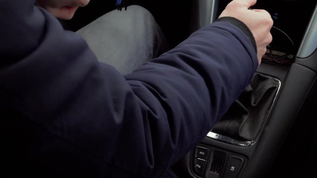 Man in warm clothes changing gear during car driving, mechanical speed control at day. Bunch of keys dangling at drive. Inside of car, focus on shift lever of manual transmission and hand. Riding auto