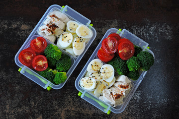 Lunch boxes with a healthy meal. Fitness snack in lunch box. Broccoli, quail eggs, chicken breast and cherry tomatoes.