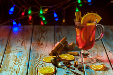Mulled wine with spices on a wooden table and a garland.