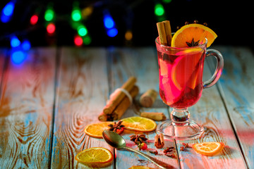 Mulled wine with spices on a wooden table and a garland.