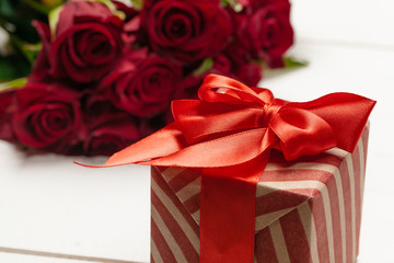A bouquet of red roses, gift and hearts on table. Concept Women's Day or St. Valentine. Copy space